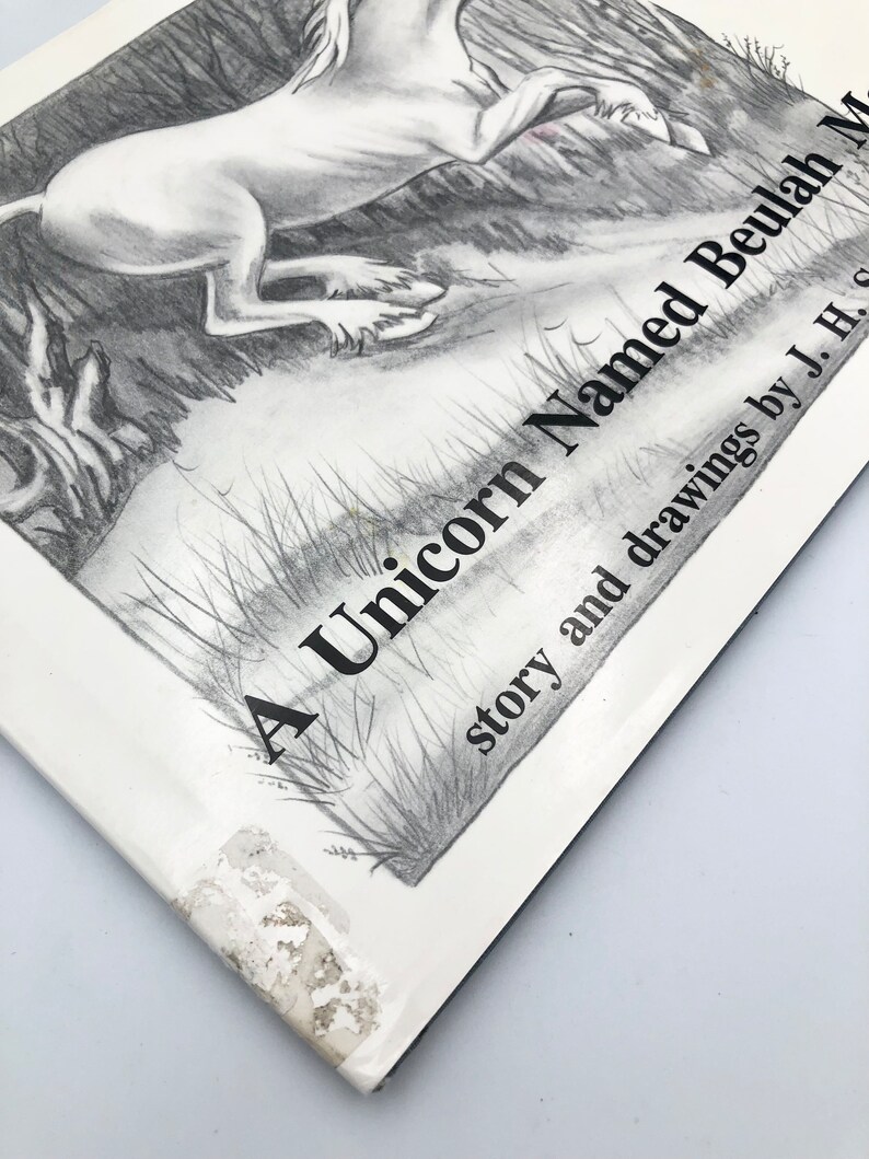 May include: A black and white illustration of a unicorn running through a forest. The book cover reads "A Unicorn Named Beulah" with the text "story and drawings by J. H. S."
