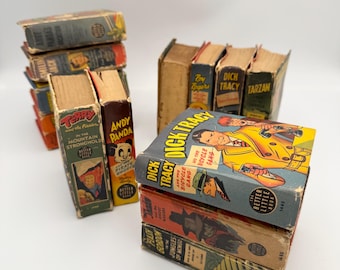 May include: A stack of vintage paperback comic books featuring characters such as Dick Tracy, Terry and the Pirates, Andy Panda, and Tarzan. The books are in various shades of blue, red, yellow, and green with illustrations of the characters on the covers.