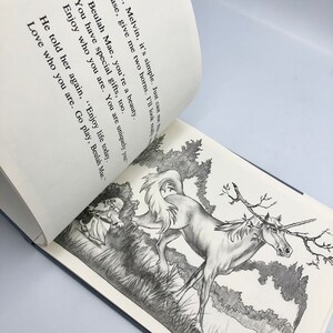 May include: A black and white illustration of a unicorn with a branch for a horn, running through a field of grass. A small figure in a dress is running behind the unicorn. The text reads: "Oh, Melvin, it's simple. Just cast me those two horns. I'll look really beautiful. Beulah Mae, you're a beauty. You have special gifts, too. Enjoy who you are. You are uniquely you. He told her again, "Enjoy life today. Love who you are. Go play, Beulah Mae."
