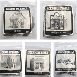 May include: Five bags of model building kits for a model railroad or train set. Each bag contains a different building kit, including an ice house, a general store, a pharmacy, a ticket office, and a flatbed truck and tractor. The bags are labeled with the name of the building and the kit number.