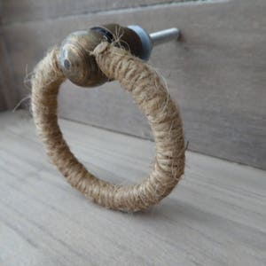 May include: A rope door pull with a brass ring. The rope is a natural brown colour.