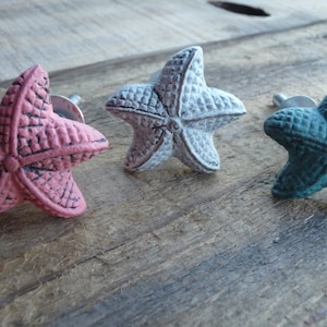 May include: Three starfish-shaped cabinet knobs in pink, white, and teal.