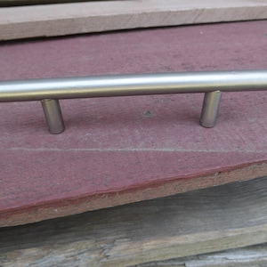 Peut inclure: Une poignée de tiroir en métal argenté de forme cylindrique avec deux petites saillies arrondies de chaque côté.