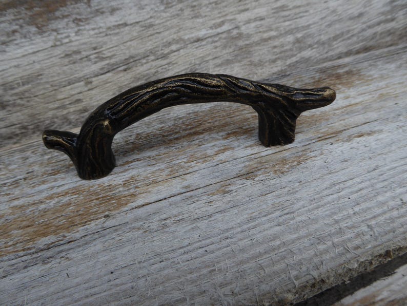 May include: Bronze-toned cabinet pull handle with a textured, branch-like design. The curved handle is approximately 5 inches long, with a detailed, organic appearance. Ideal for adding a rustic or natural touch to furniture or cabinetry.