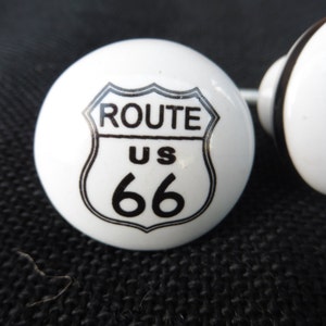 May include: Two white ceramic knobs with black accents. Each knob features a black and white Route US 66 sign.