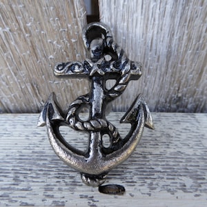 May include: A silver metal anchor with a rope design. The anchor is a decorative piece with a nautical theme.