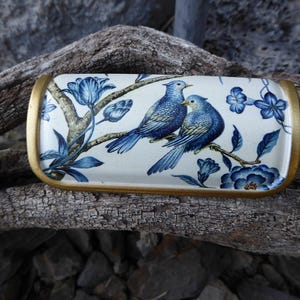 May include: Rectangular ceramic tray with a gold rim. The tray features a detailed illustration of two blue birds perched on a branch with blue flowers and foliage against a white background. Decorative home decor.