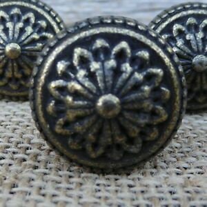 May include: Close-up of three antique bronze cabinet knobs. Each knob features a detailed floral design in the center, surrounded by an ornate border. The knobs have a slightly distressed finish, giving them a vintage appearance.