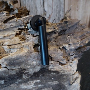 Puede incluir: Tirador de puerta de armario de metal negro con base redonda y mango cilíndrico.