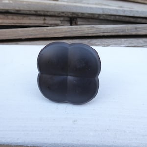 May include: A black four-leaf clover shaped cabinet knob.
