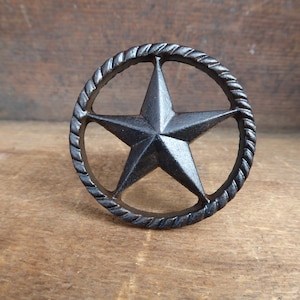 May include: A black cast iron door knob with a rope design and a five-pointed star in the center.
