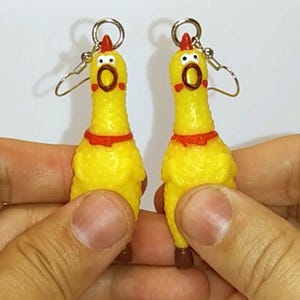 May include: A pair of yellow rubber chicken earrings with red accents and silver hooks.