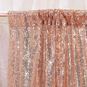 May include: Rose gold sequin backdrop for photography or event decor. The fabric is made of small, shimmering sequins that create a glamorous look.