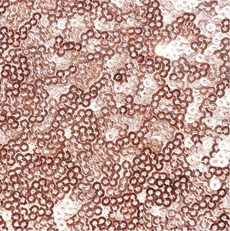 May include: A close-up of a rose gold fabric covered in sequins. The sequins are small and round, creating a shimmering effect.