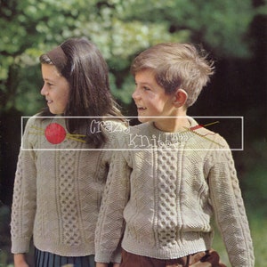 May include: Two children wearing beige knitted sweaters with cable knit patterns. The sweaters are from a vintage knitting pattern book titled "Double Knittings by Patons" with the pattern number 9595.