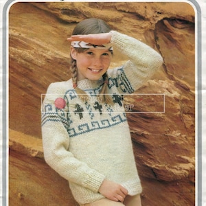 May include: A white knitted sweater with a blue and brown geometric pattern. The sweater has a crew neck and long sleeves. The model is wearing a headband with a Native American design.