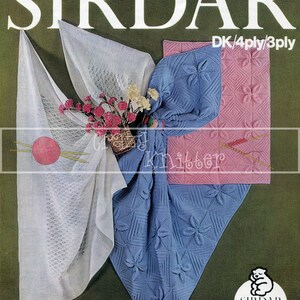Könnte beinhalten: Ein Vintage-Strickmuster-Cover von Sirdar mit einem weißen Spitzenschal, einer blauen Decke mit Blumenmustern und einer rosa Decke mit Rautenmustern. Der Text "Sirdar Snuggly Baby Yarns" ist ebenfalls enthalten.