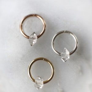 Op de afbeelding: Drie creolen met heldere diamantvormige kristallen die eraan hangen. De creolen zijn gemaakt van goud, zilver en ros&eacute;goud.