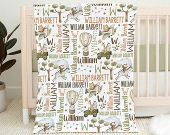 May include: White baby blanket with a repeating pattern of safari animals, hot air balloons, airplanes, and the name "William Barrett" in brown and green text.