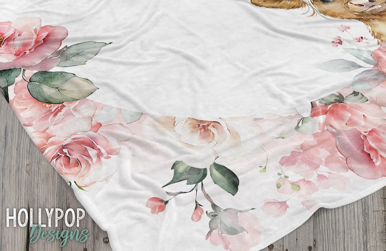 May include: A white blanket with a floral design featuring pink roses and green leaves. The blanket has a soft, fuzzy texture and is perfect for cuddling up on the couch.