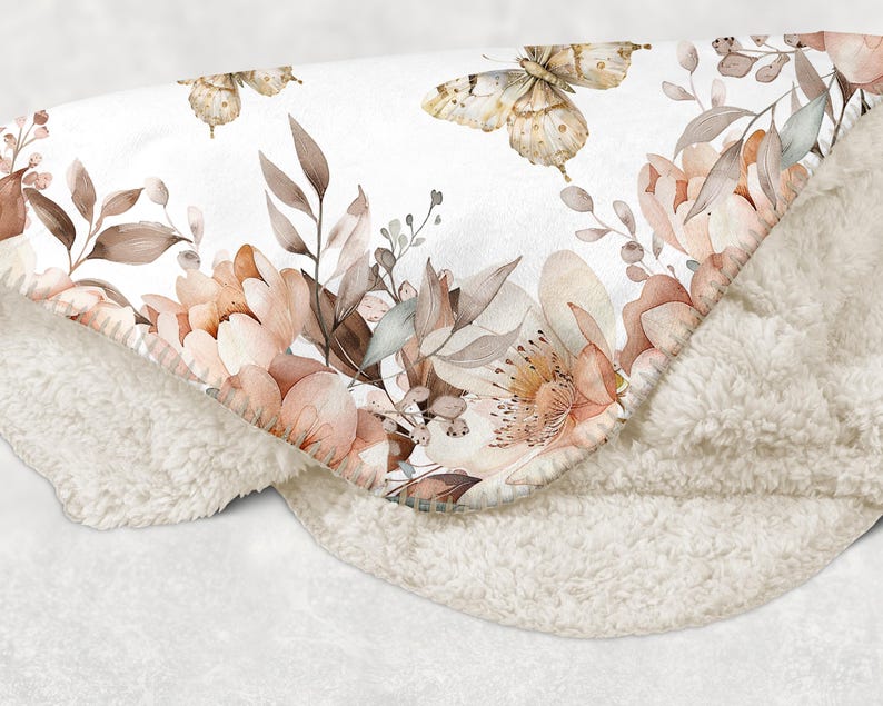 Puede incluir: Una suave manta de sherpa blanca con un estampado floral que presenta delicadas mariposas y flores rosa claro. La manta es perfecta para agregar un toque de elegancia y calidez a cualquier habitaci&oacute;n.