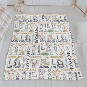 a white blanket with a repeating pattern of cartoon animal illustrations, including a giraffe, lion, and elephant, along with the name "Landon" written in various fonts and sizes.