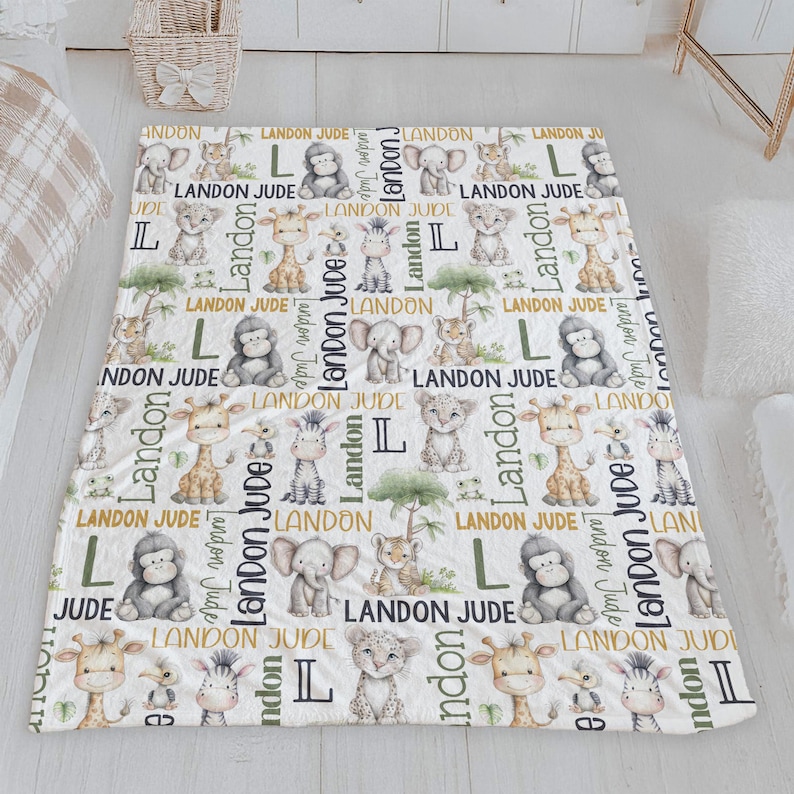 a white blanket with a repeating pattern of cartoon animal illustrations, including a giraffe, lion, and elephant, along with the name "Landon" written in various fonts and sizes.