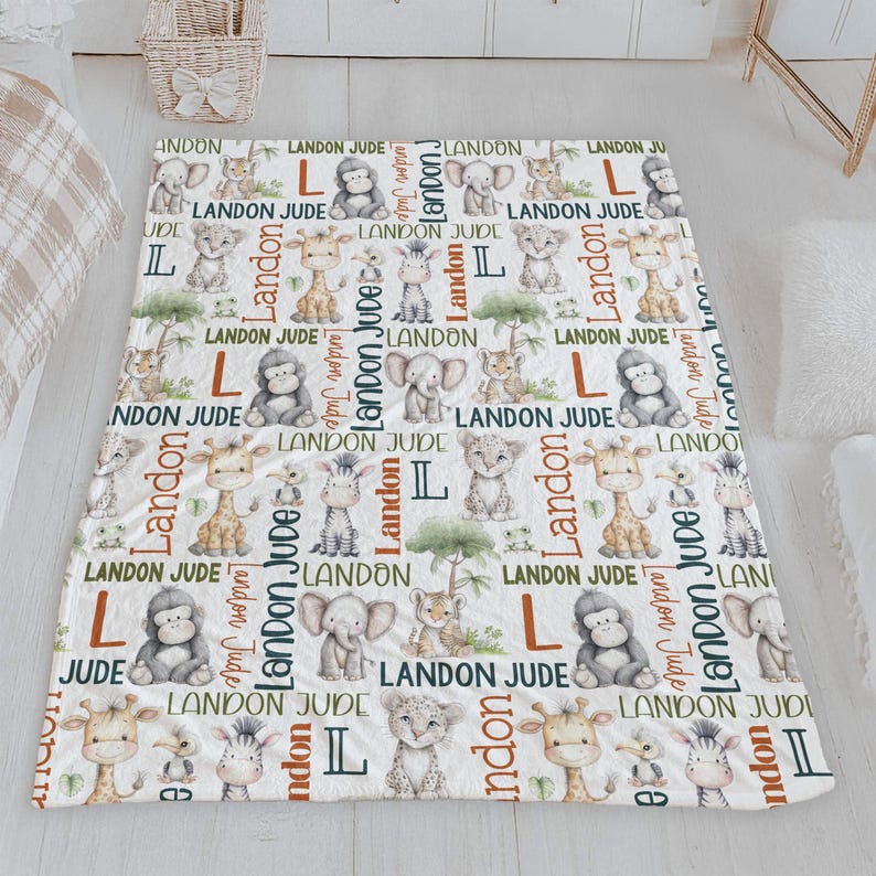 a white and green blanket with a repeating pattern of cartoon animal illustrations, including a giraffe, lion, and elephant, along with the name 'Landon' written in various colors.
