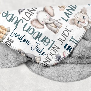 a blanket with various animal illustrations, including elephants, giraffes, and leopards, along with the name "Landon" written on it.