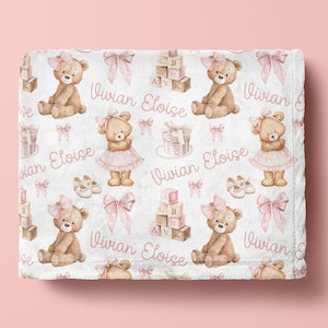 May include: White baby blanket with a repeating pattern of teddy bears, pink bows, baby blocks, and the name "Vivian Eloise" in pink script. The bears wear pink bows and some are dressed in pink tutus.