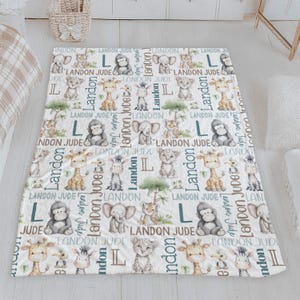 a white blanket with a repeating pattern of various animals, including elephants, giraffes, and zebras, along with the letters 'LANDON JUDGE' printed on it.