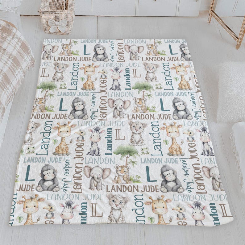 a white blanket with a repeating pattern of various animals, including elephants, giraffes, and zebras, along with the letters 'LANDON JUDGE' printed on it.