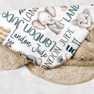 a blanket with a pattern of various animals, including elephants, lions, and giraffes, along with the name "Landon" written on it.