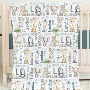 a white blanket with a repeating pattern of various cartoon animal illustrations, including elephants, giraffes, zebras, and lions, along with the letters 'LANDON JUDGE' written in different fonts and sizes.