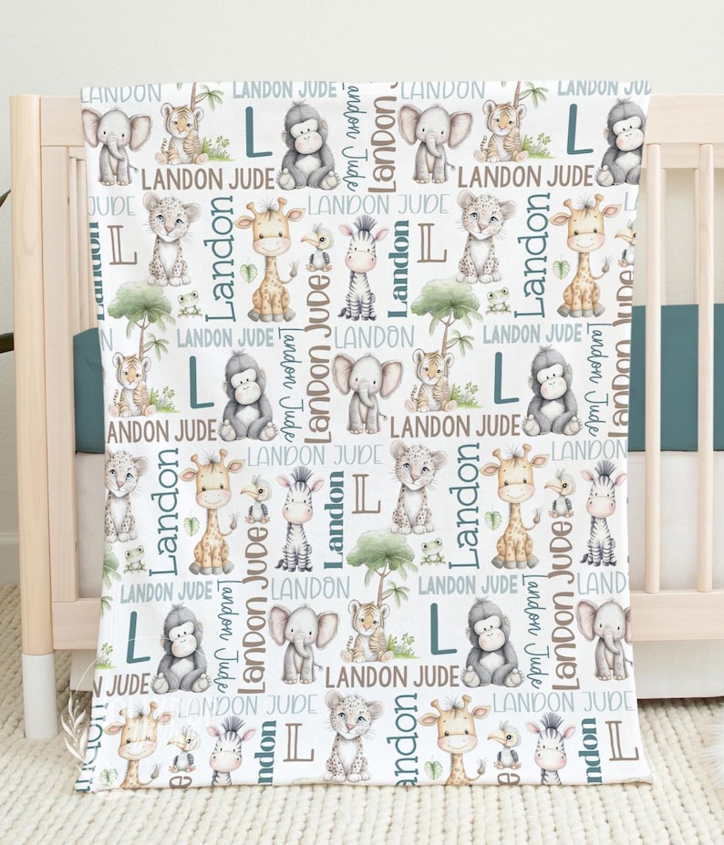 a white blanket with a repeating pattern of various cartoon animal illustrations, including elephants, giraffes, zebras, and lions, along with the letters 'LANDON JUDGE' written in different fonts and sizes.