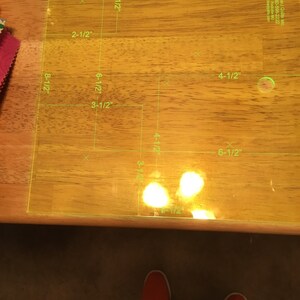 May include: A clear plastic ruler with green markings for measuring fabric. The ruler has measurements in inches, including 2-1/2", 3-1/2", 4-1/2", 6-1/2", and 8-1/2".