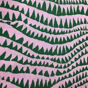 May include: Pink fabric with a repeating pattern of green, jagged triangles. The triangles are arranged in wavy rows.