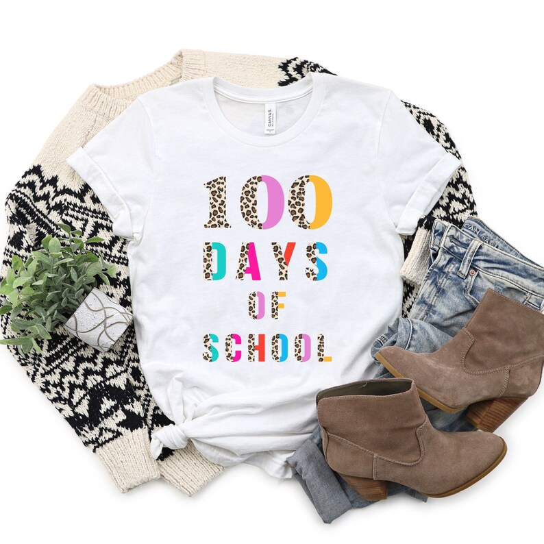 Peut inclure: T-shirt blanc avec le texte "100 JOURS D'&Eacute;COLE" en lettres color&eacute;es avec un motif l&eacute;opard.