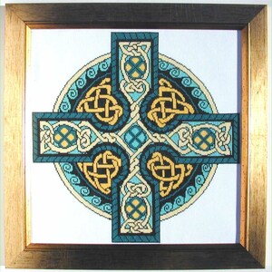 Puede incluir: Obra de arte en punto de cruz enmarcada con un dise&ntilde;o de cruz celta. La cruz es de color turquesa, dorado y crema, con intrincados patrones de nudos. La obra de arte est&aacute; enmarcada en un marco de madera dorado y marr&oacute;n oscuro.