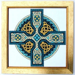 Puede incluir: Obra de arte de punto de cruz enmarcada con un dise&ntilde;o de cruz celta. La cruz presenta tonos de verde azulado, dorado y crema, con intrincados patrones de nudos. La obra est&aacute; enmarcada en un marco de madera dorado.