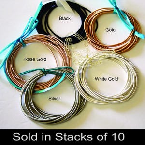 May include: An assortment of wire in various colors, including black, gold, rose gold, silver, and white gold. Each color is bundled and tied with ribbon. Text on the image reads "Sold in Stacks of 10."