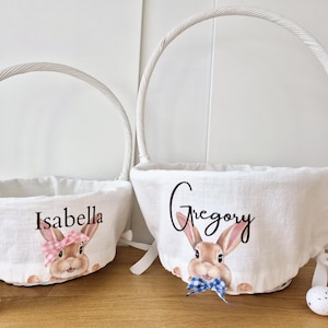 May include: Two white Easter baskets with bunny illustrations and personalized names, "Isabella" and "Gregory".
