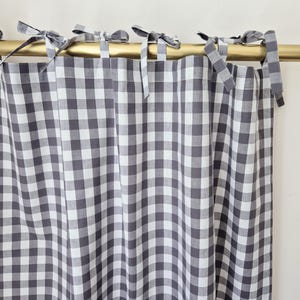 May include: Grey and white gingham check curtains with a gold rod and white ties.