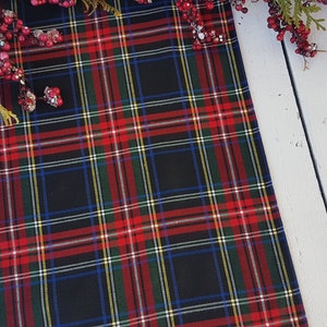 May include: Black and red plaid table runner with a white background. The runner has thin stripes of yellow and blue.