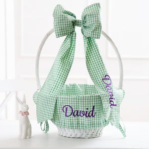 May include: White wicker Easter basket with a green and white gingham bow and lining. The basket is personalized with the name "David" in purple embroidery.