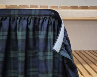 May include: A green and blue plaid shirt with a white button-up collar and a white trim along the edge of the collar.