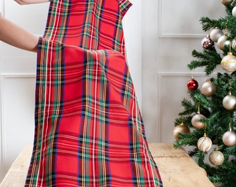 May include: Red and green plaid table runner with white trim. The runner is folded in half and draped over a wooden table.