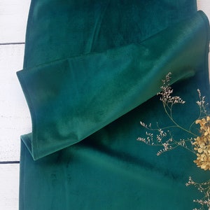 Könnte beinhalten: Ein tiefgrüner Samttischläufer, in der Mitte gefaltet, mit einem Zweig getrockneter Blumen auf der rechten Seite.