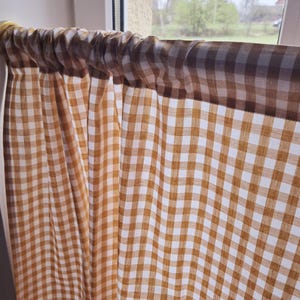 May include: A brown and white gingham valance with a gathered top, hanging in a window.