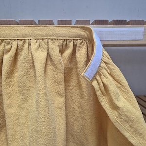 以下が含まれることがあります： 上端に白いマジックテープが付いた黄色の布製のカーテンです。